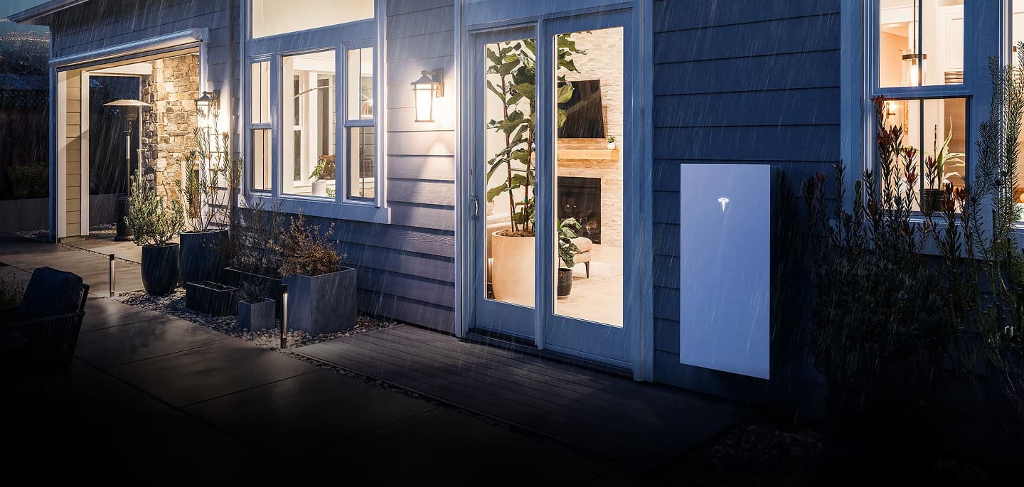 Home lit at night with a Tesla Powerwall mounted outside